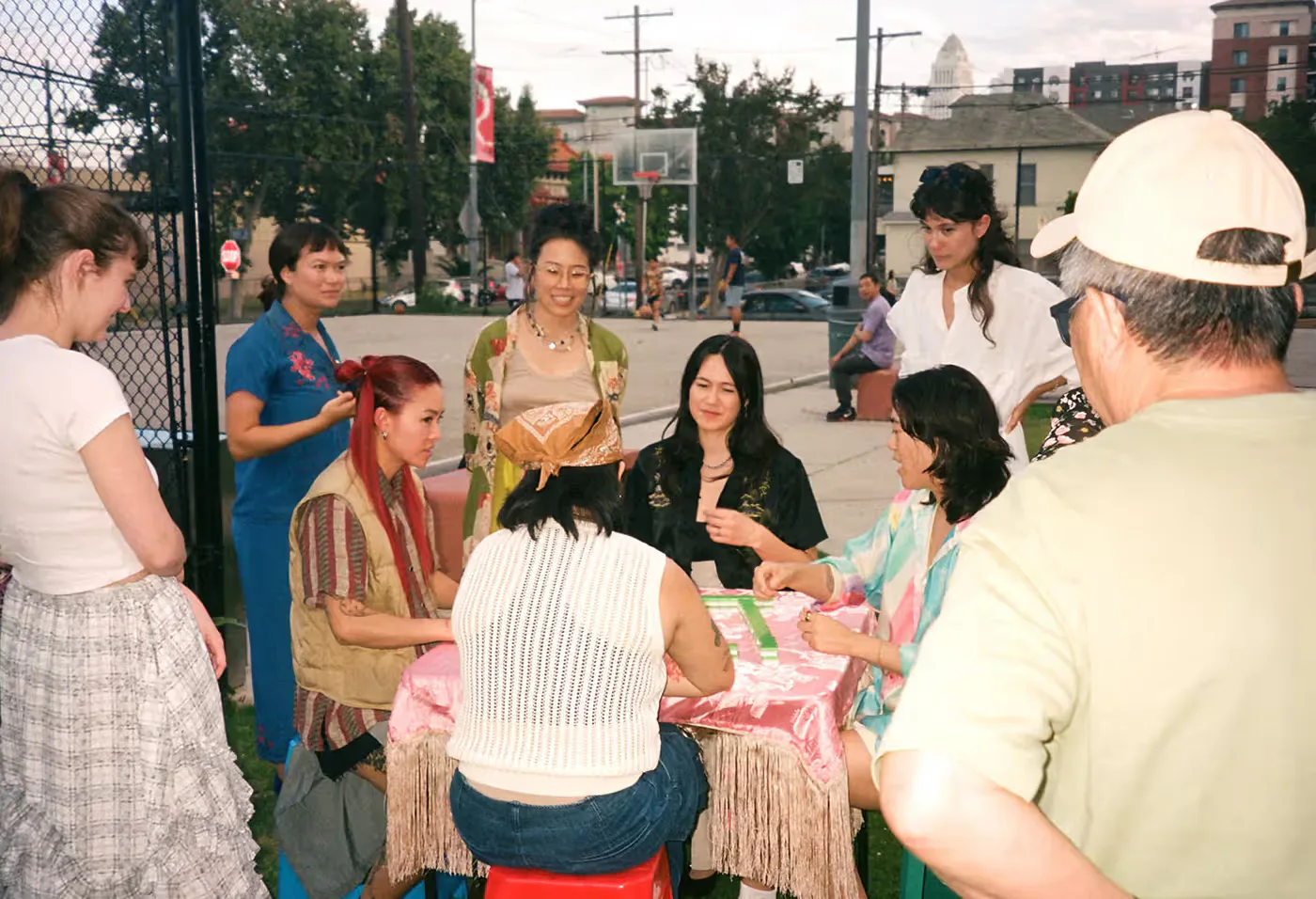 A group learning and playing Mahjong around an outdoor table