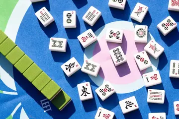 Ivory Chinese Mahjong tiles on a blue, green, and pink mat