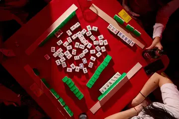 Chinese Mahjong tiles and players' hands around a red table