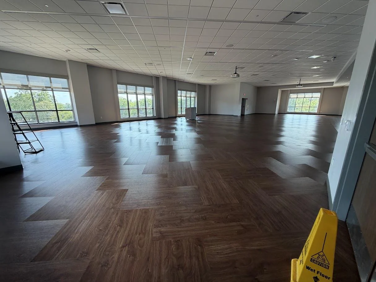 Ballroom A with dark wood floors and large windows overlooking trees