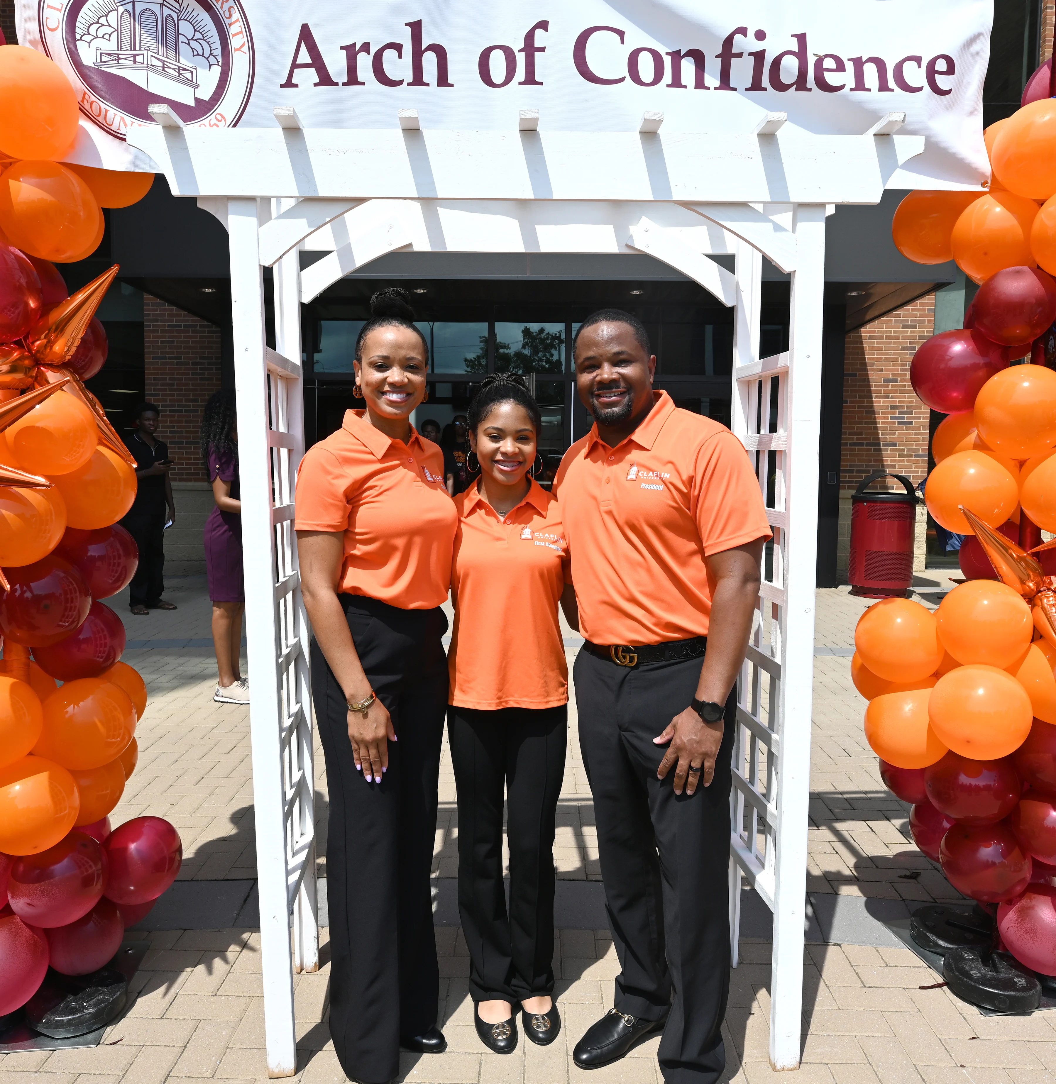 Claflin leaders welcoming students beneath an orange and maroon balloon arch