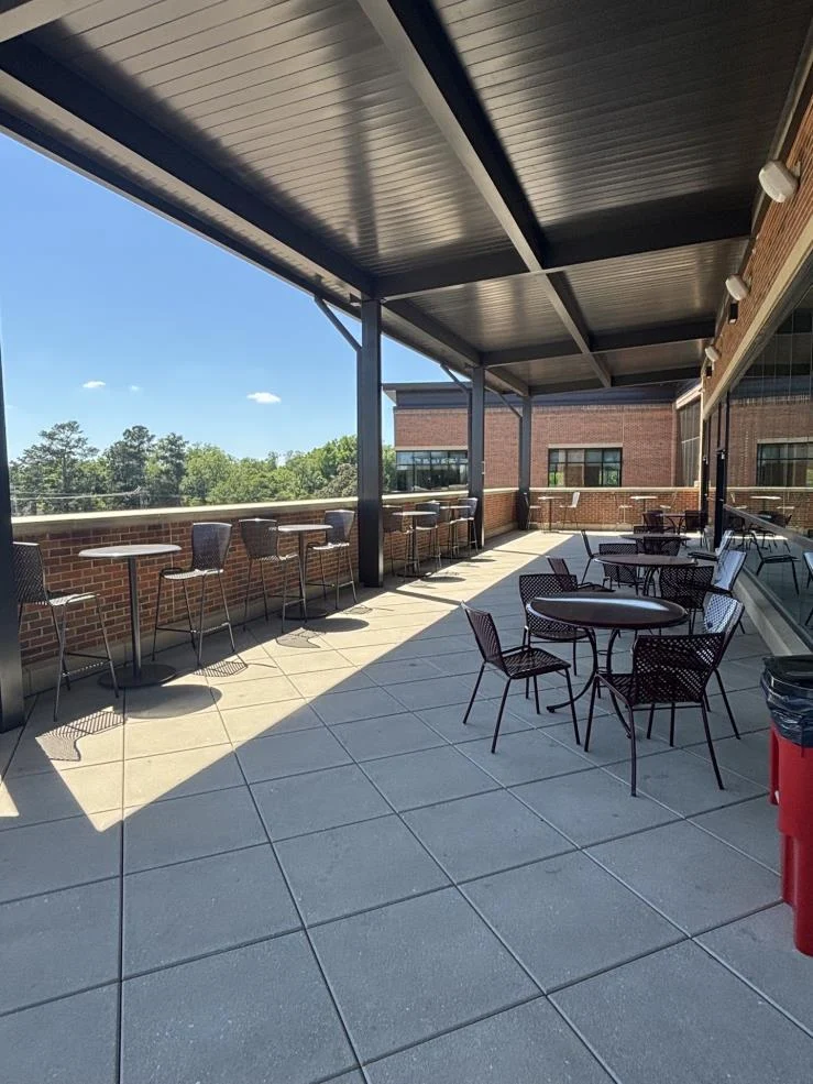 Third-floor terrace with covered outdoor seating and views of the surrounding trees