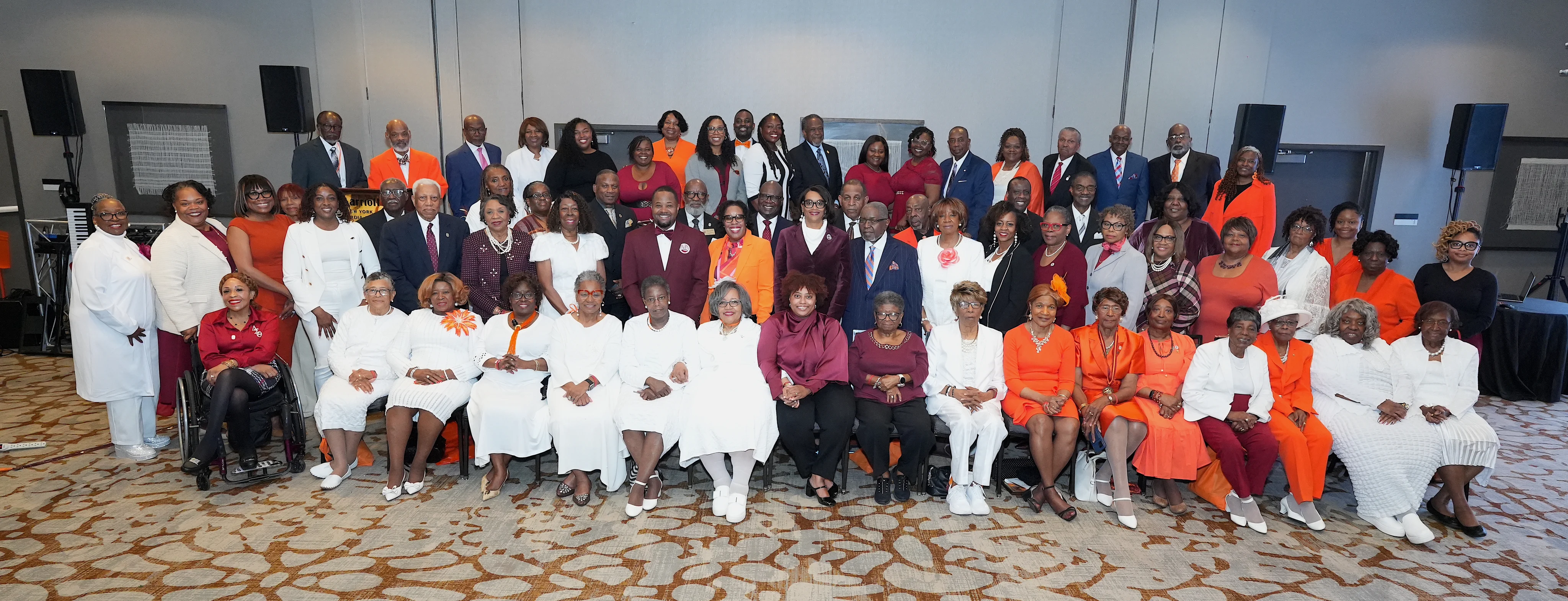 Members of the Claflin University International Alumni Association pose together in maroon, orange, and white attire