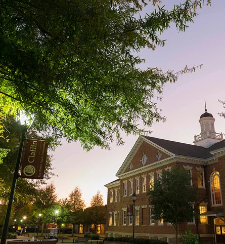 Claflin University brick building with a white cupola at dusk, with a Claflin banner in the foreground