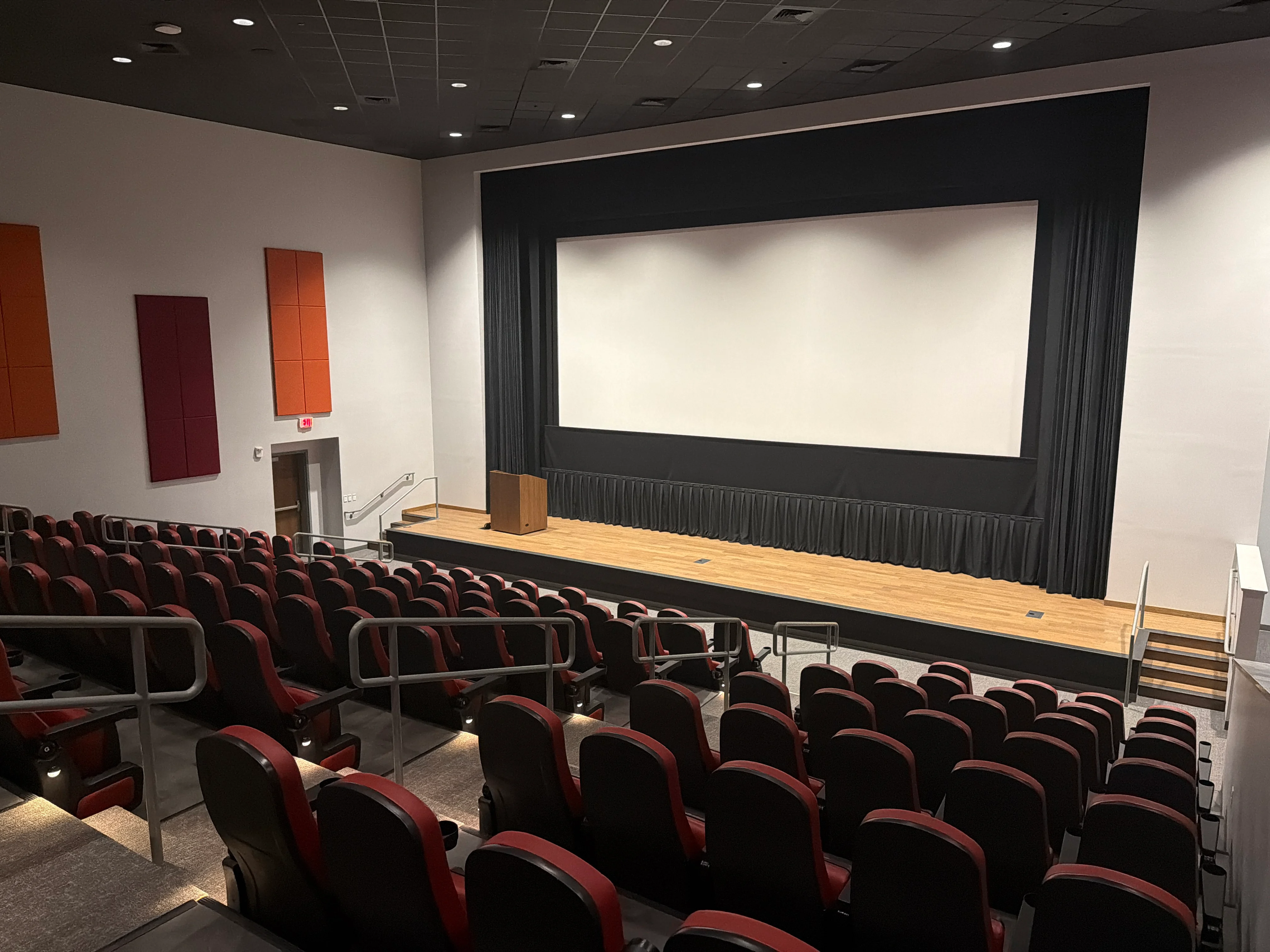 Interior of the Nissan of Orangeburg Movie Theater with tiered red seating, a large screen, and a presentation stage