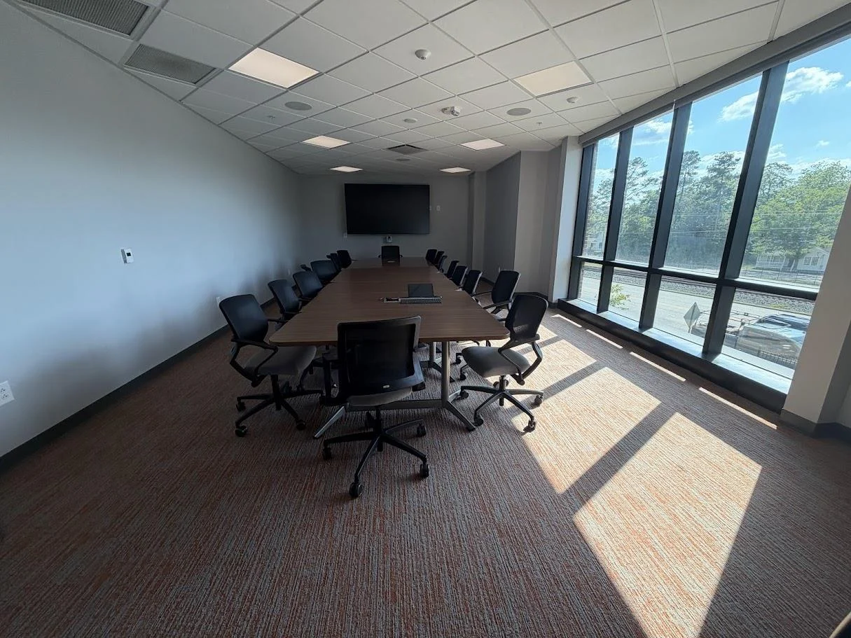 Conference Room B with a long table, black chairs, and floor-to-ceiling windows