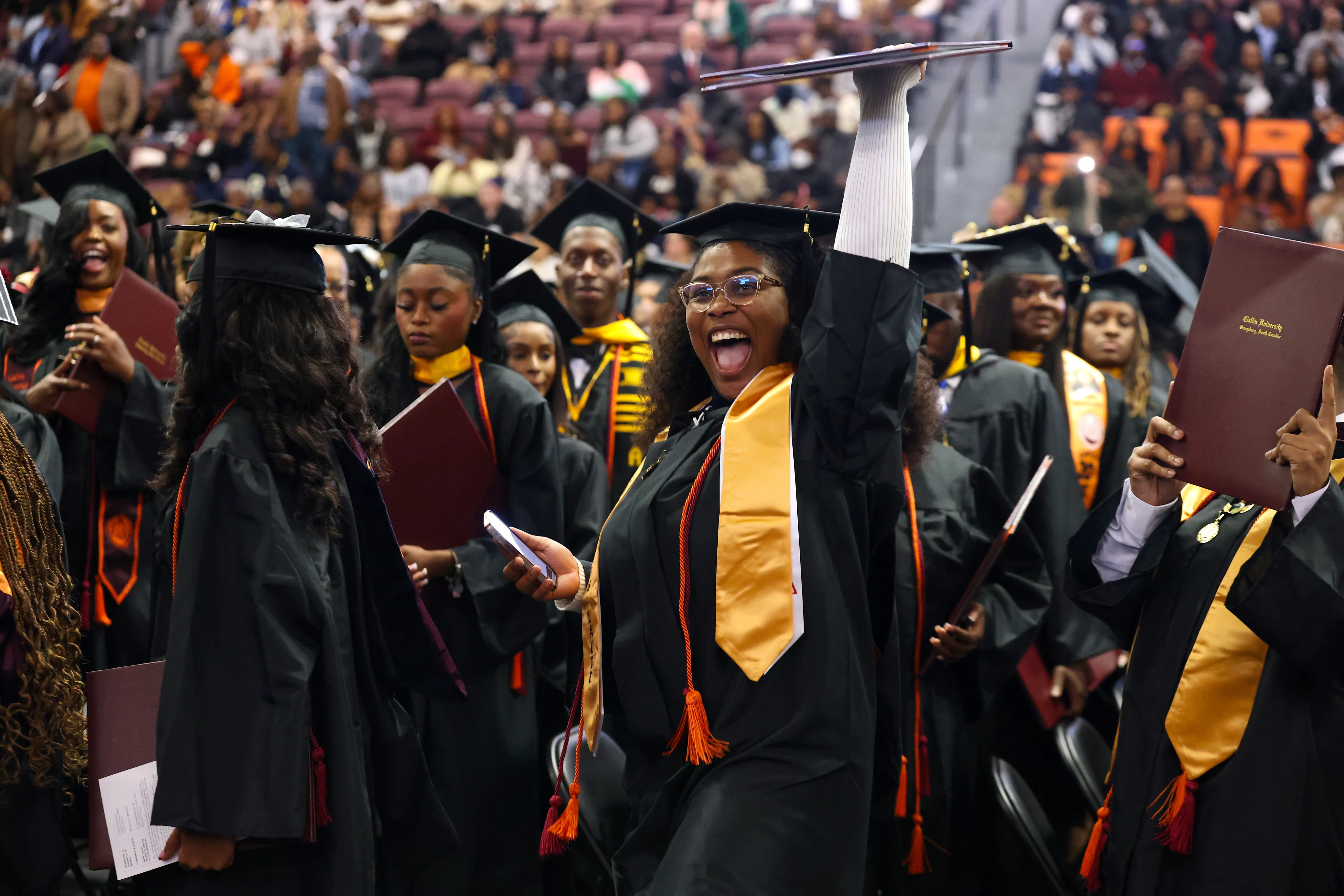 A joyful Claflin graduate raises her diploma during commencement