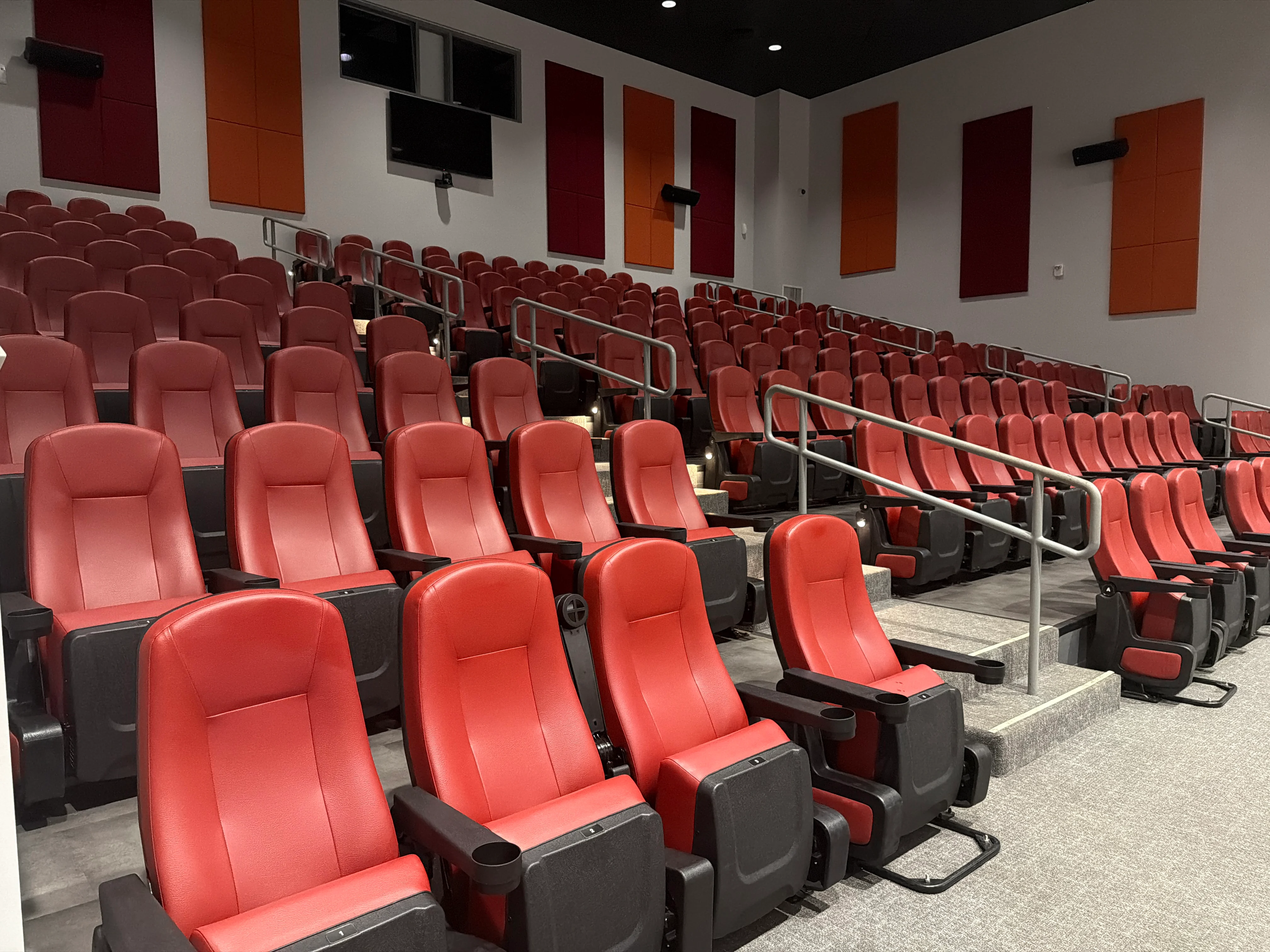 Interior of the Nissan of Orangeburg Movie Theater with tiered red seating and orange and maroon acoustic panels