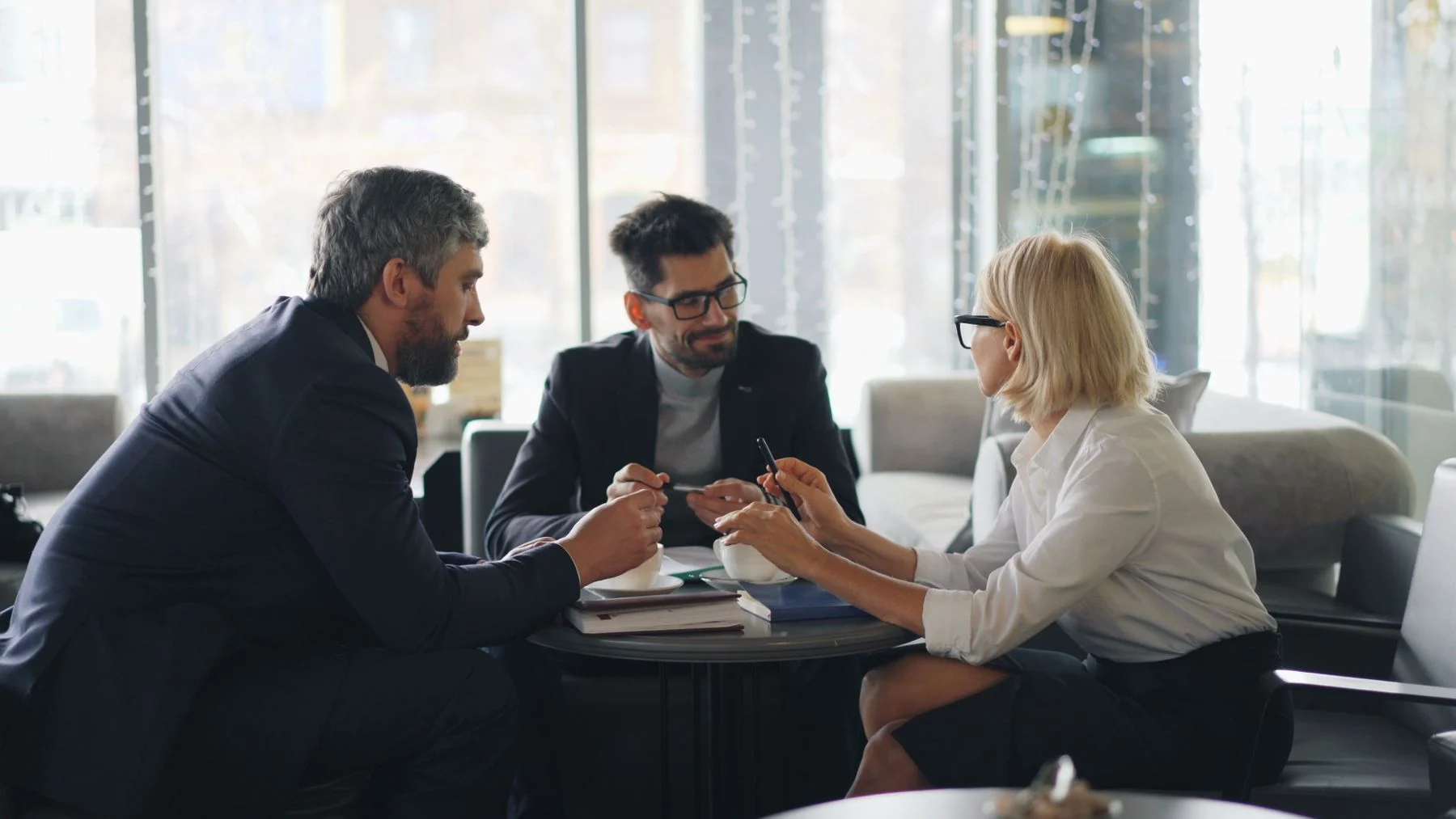Three professionals discussing strategy around a restaurant table