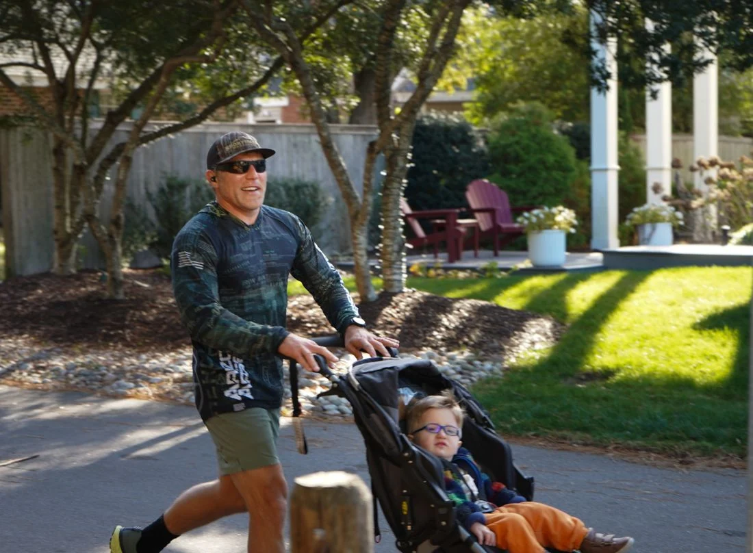 A man runs while pushing a child in a stroller.