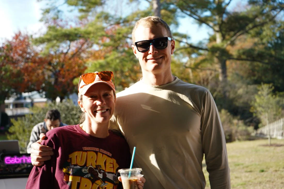 Two friends in turkey-day gear smile for a photo with coffee after the race.