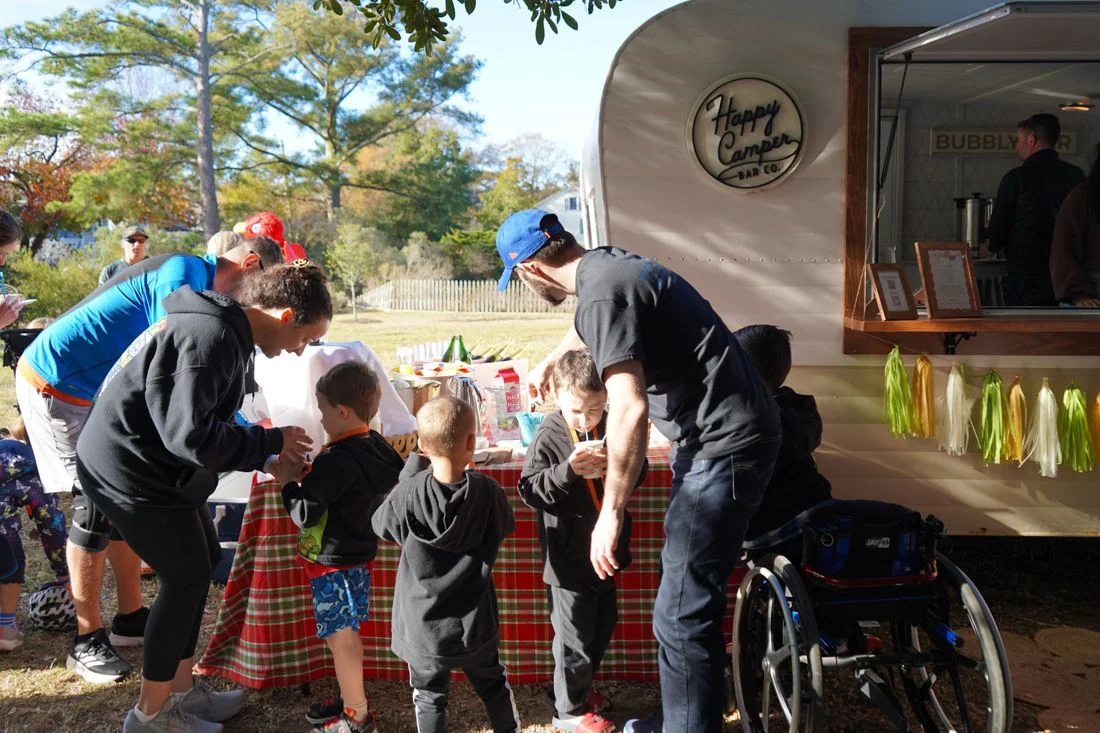 Kids lined up at the snack trailer, with a person in a wheelchair beside them.