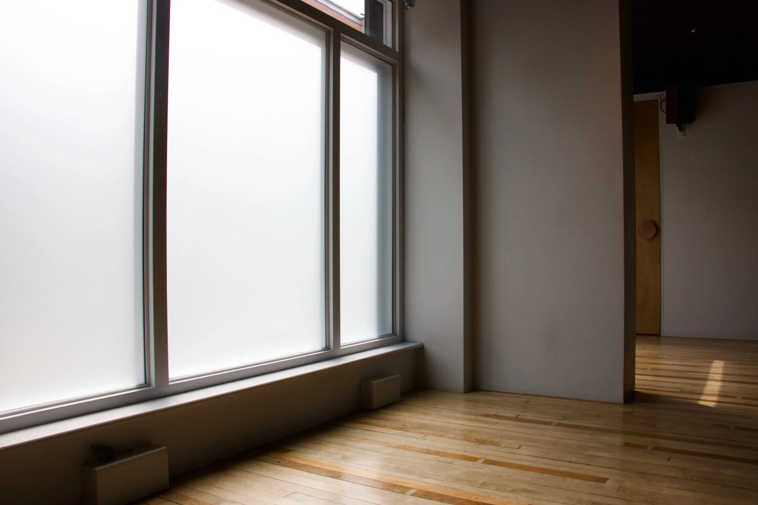 The RebelStudio yoga room in daylight, with frosted windows and a wooden floor