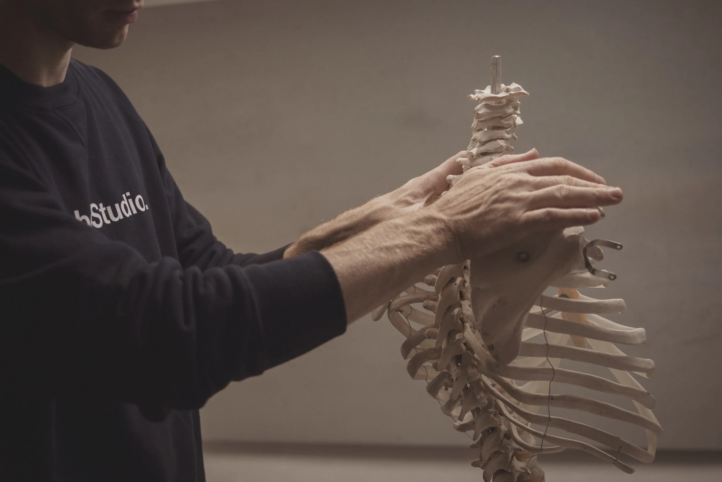 A RebelStudio osteopath demonstrating spinal movement on an anatomical skeleton