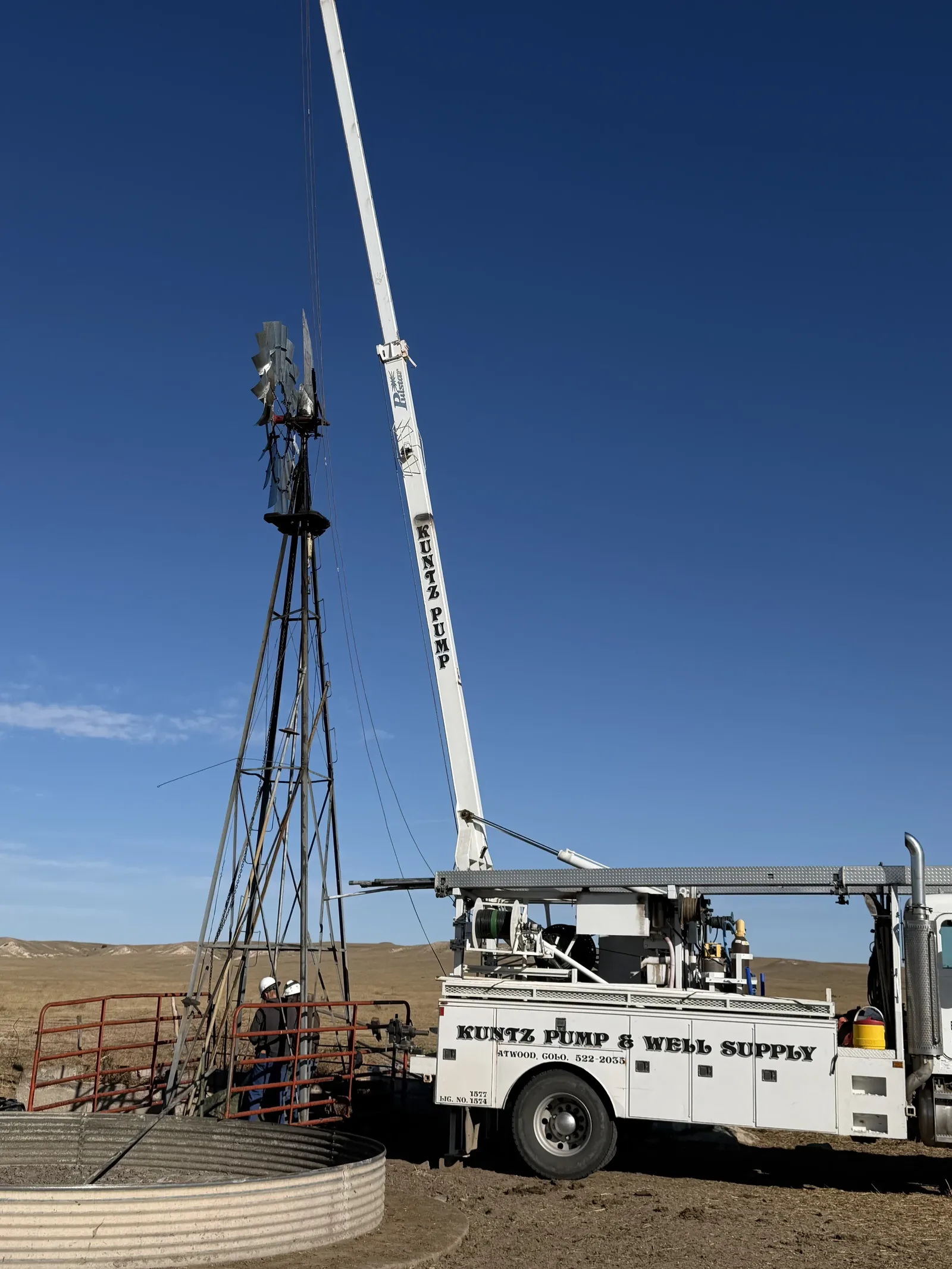 Crew working on a windmill well with a pump hoist truck on the eastern Colorado plains