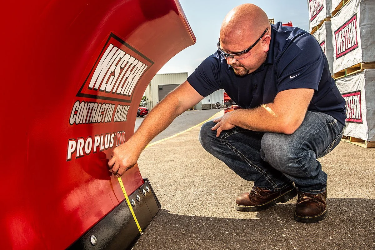 Western manufacturer photo of a technician checking a snowplow cutting edge