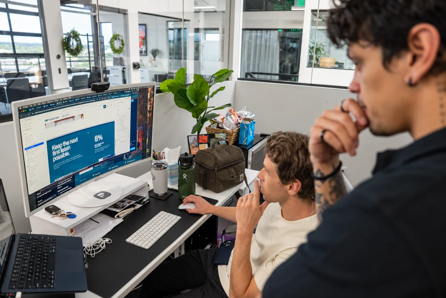 Two colleagues reviewing a website together at a workstation in a naturally lit office.