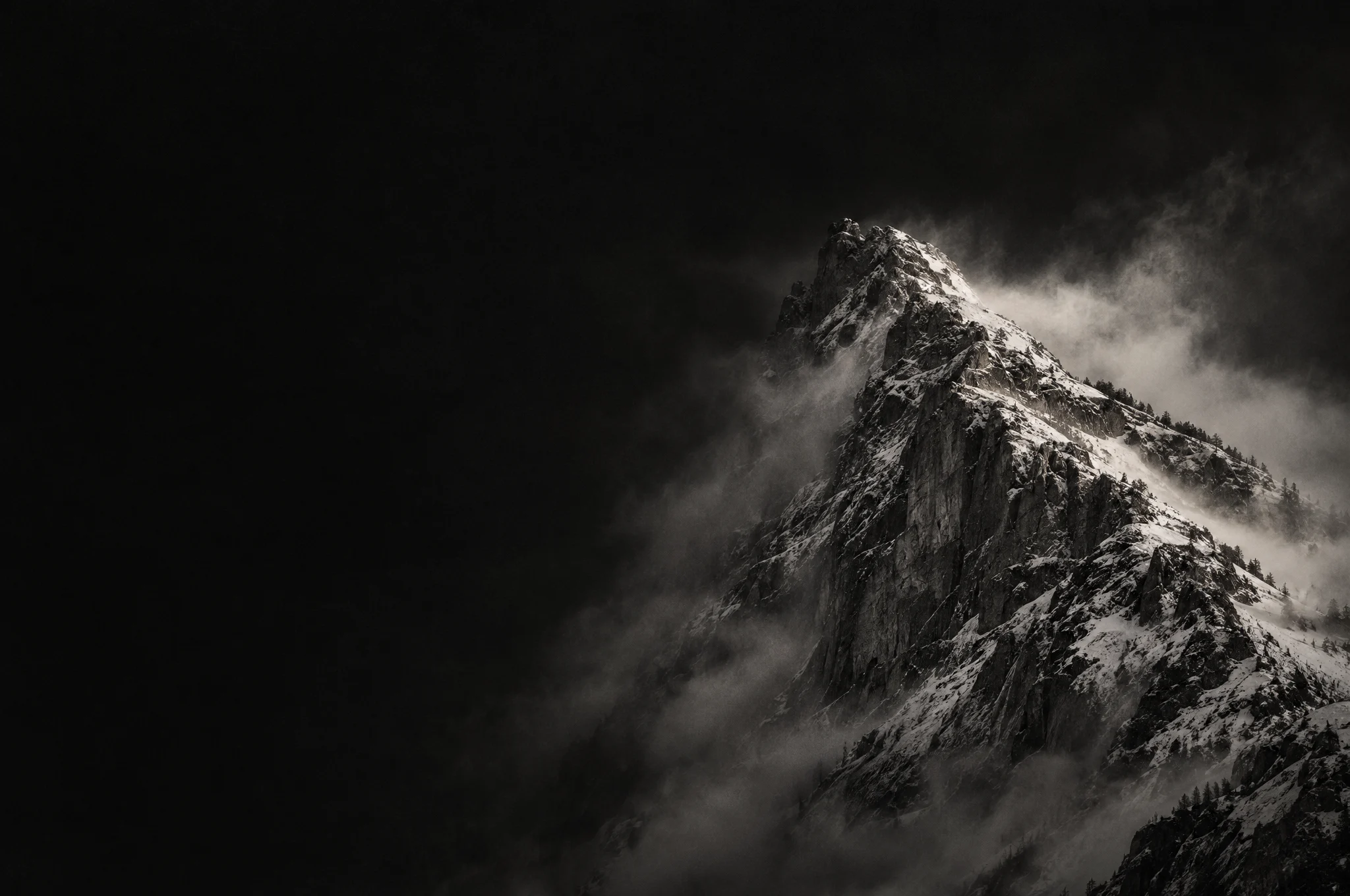 A mountain ridge emerging from mist in low light