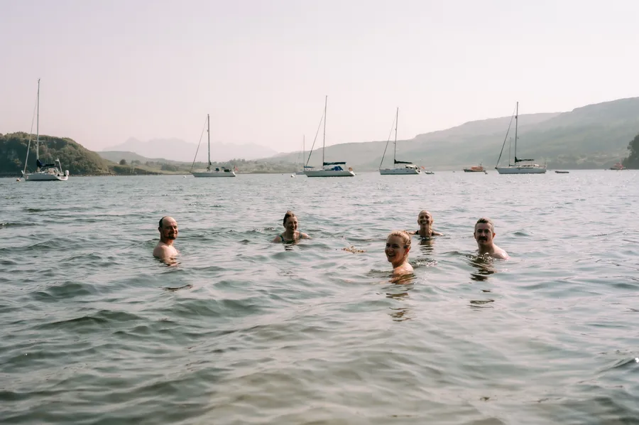 Friends cold-water swimming in Portree Harbour