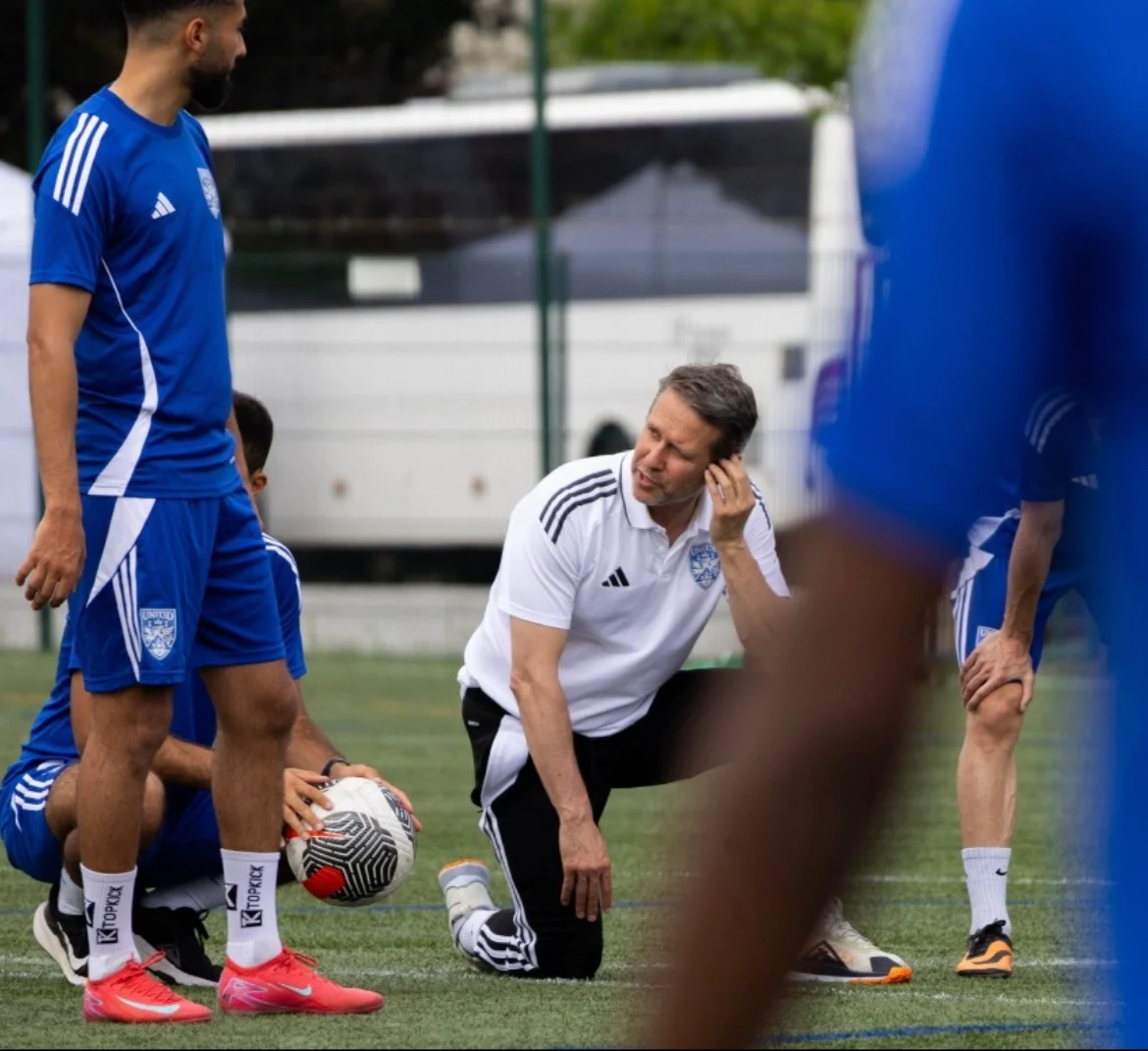 Cyrille Pavy auprès de joueurs sur un terrain de football