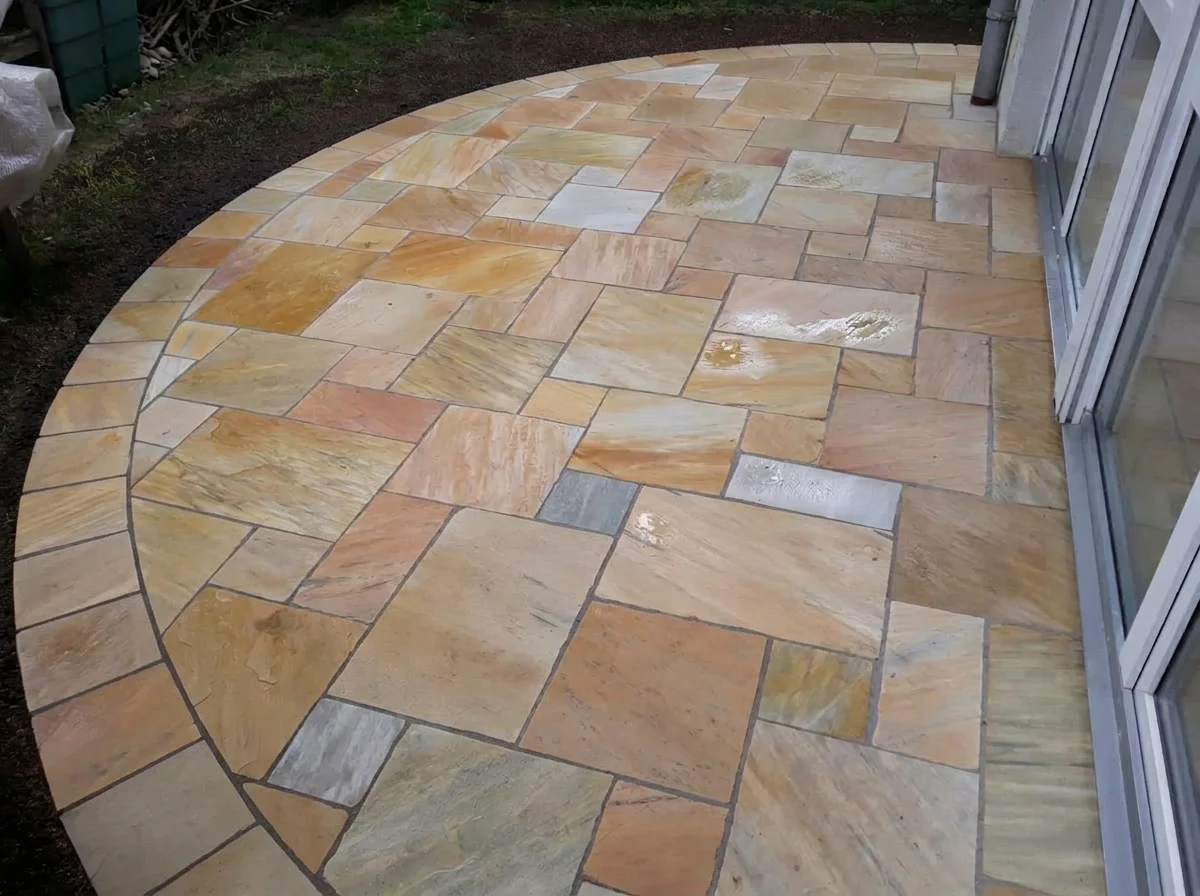 Runde Terrasse aus Sandstein-Polygonalplatten mit Bogeneinfassung