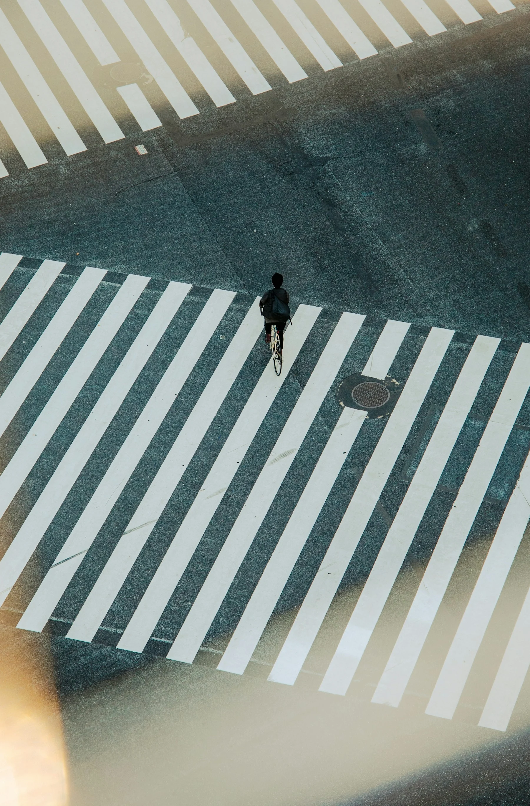 Cyclist crossing a marked city intersection viewed from above
