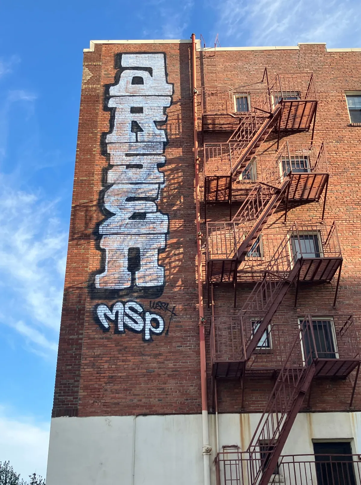 Brick building and fire escape before graffiti removal
