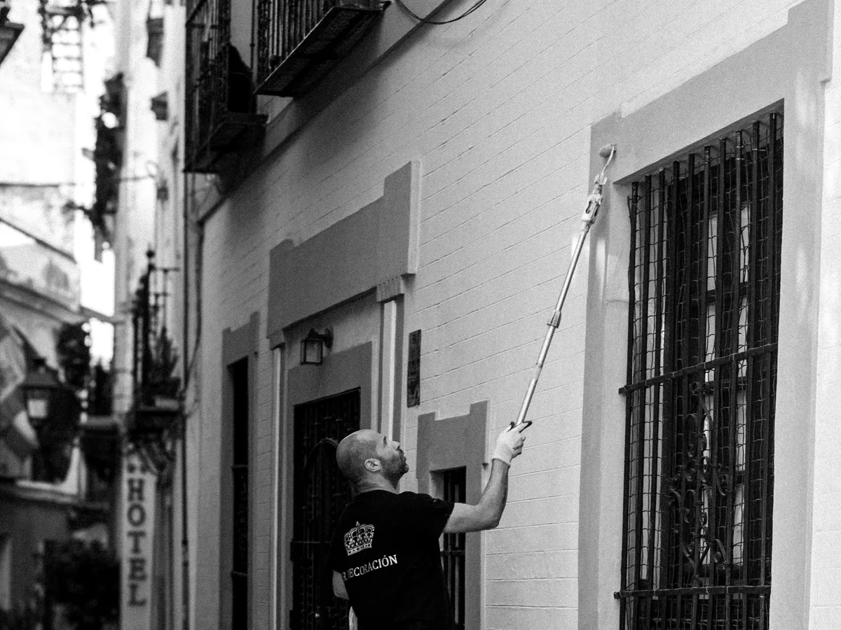Painter coating a building exterior from a ladder