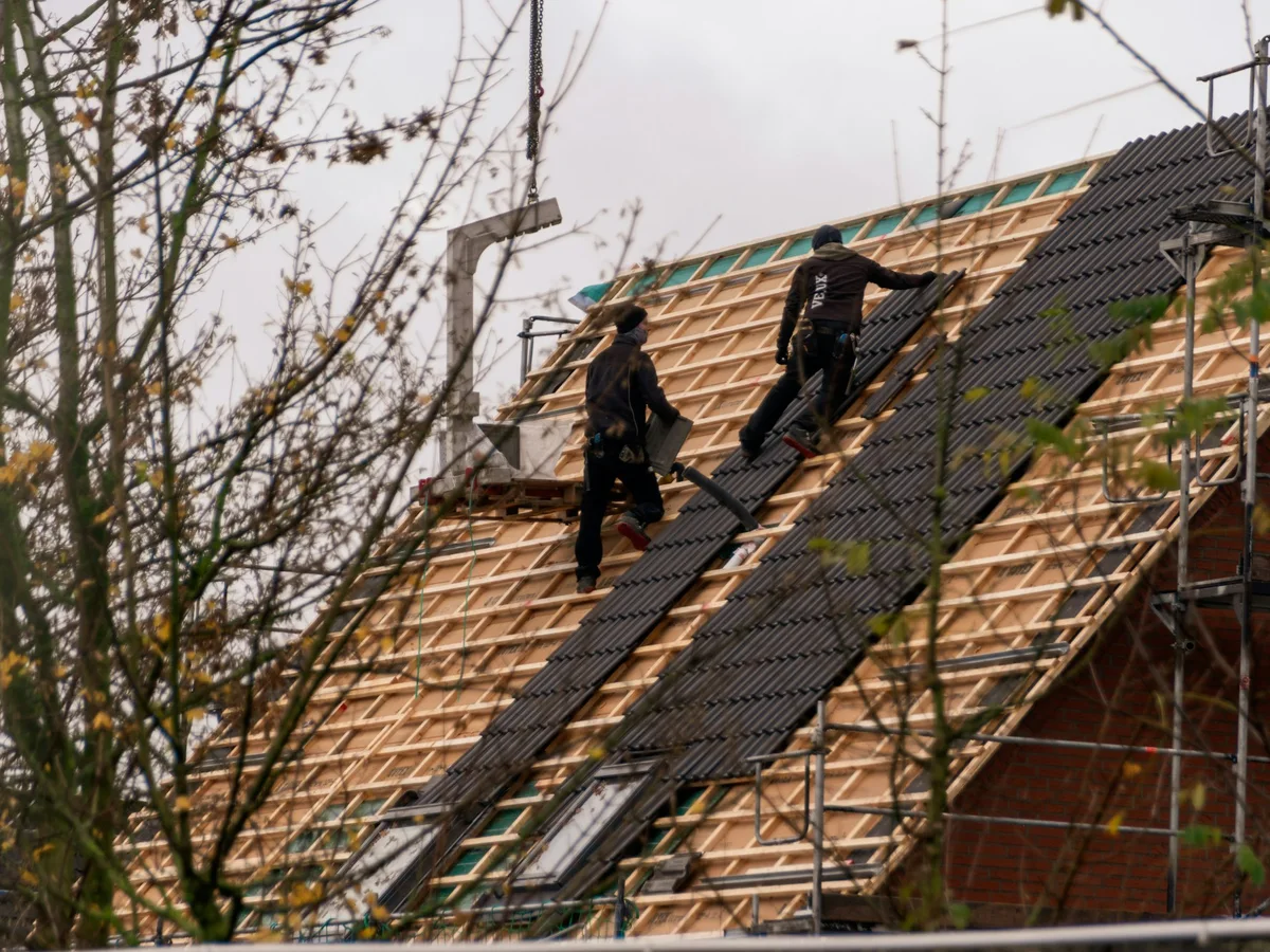 Roofing crew installing materials on a pitched roof
