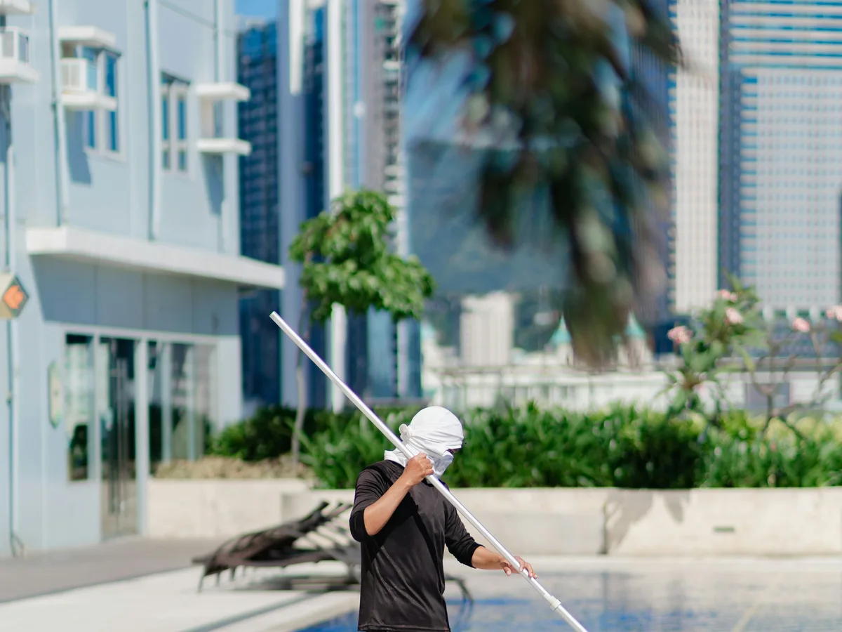 Pool service worker cleaning a swimming pool