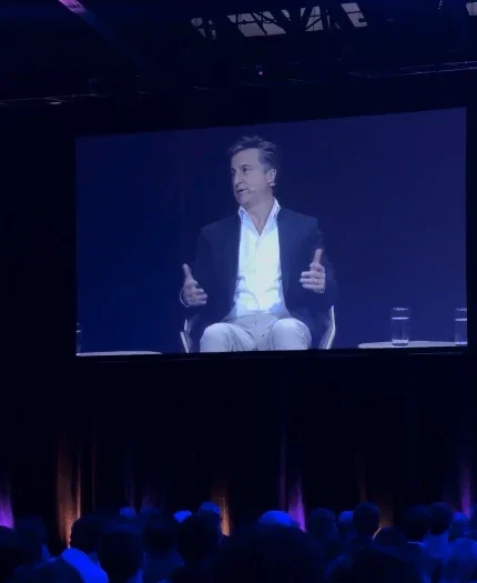 Marco Buchbinder on the main stage screen in front of a conference audience