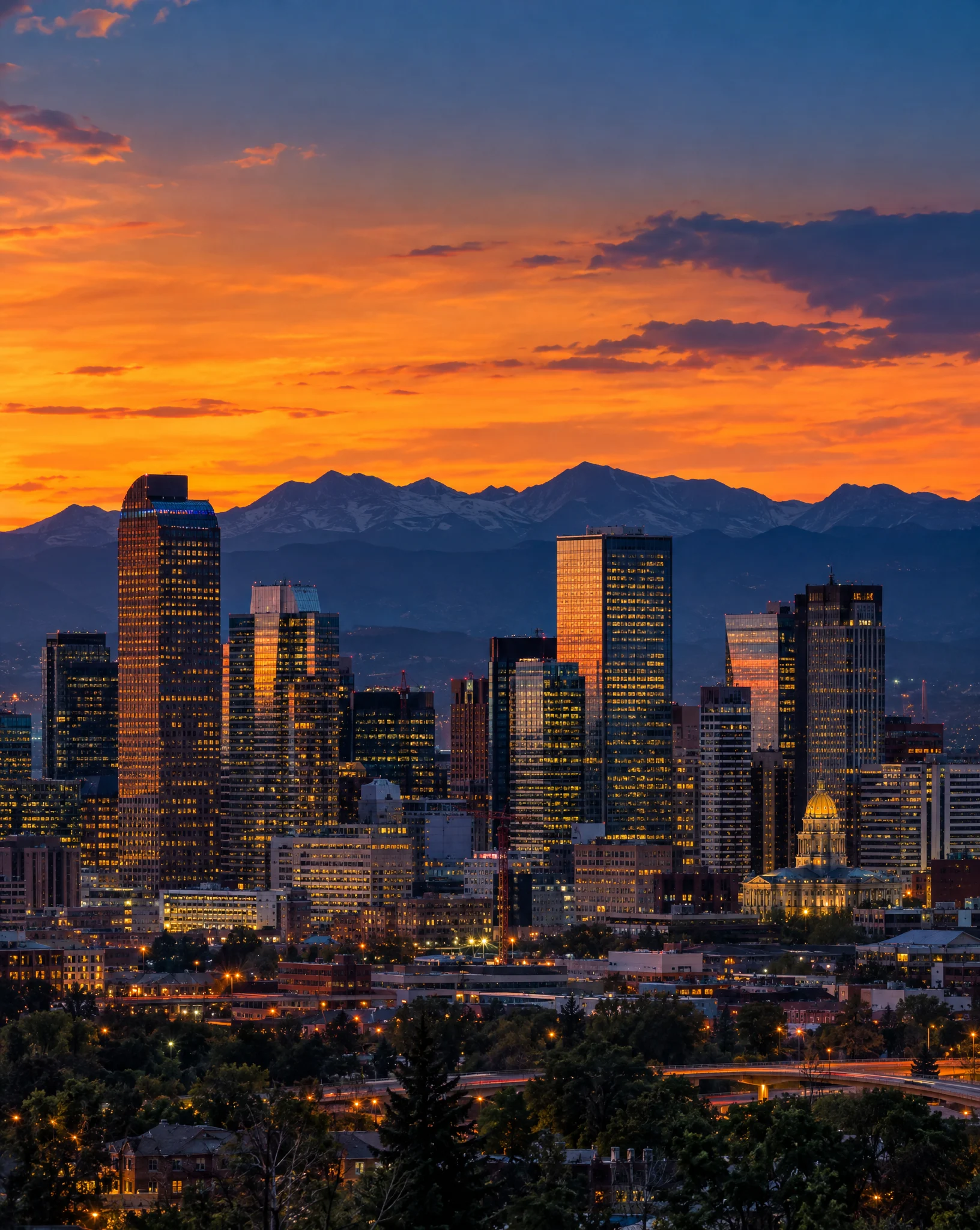 Downtown Denver skyline at dusk with the Rocky Mountains behind