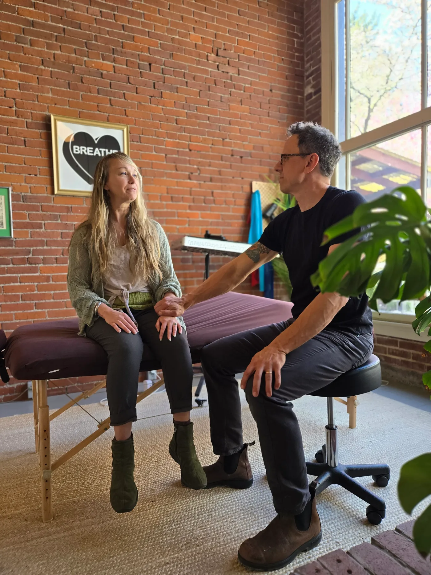 Jason Rinker talking with a patient before treatment in his brick-walled room