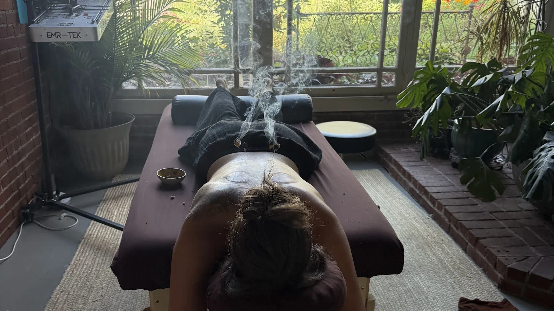 A patient resting face-down on the treatment table, facing the window onto the garden