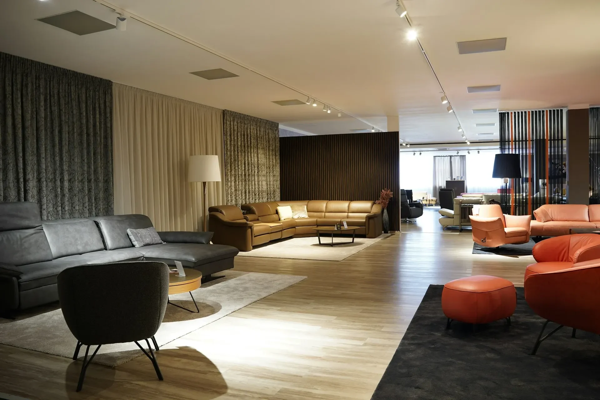 A large, well-lit furniture showroom with leather corner sofas, armchairs and rugs on display