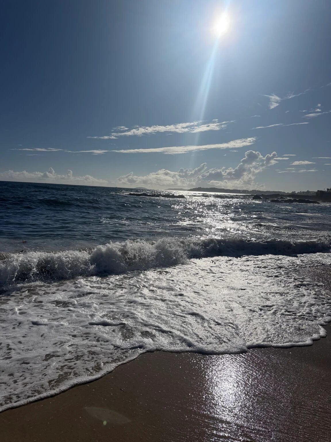 El sol aparece entre las nubes sobre el mar en la playa de Areas, en Sangenjo