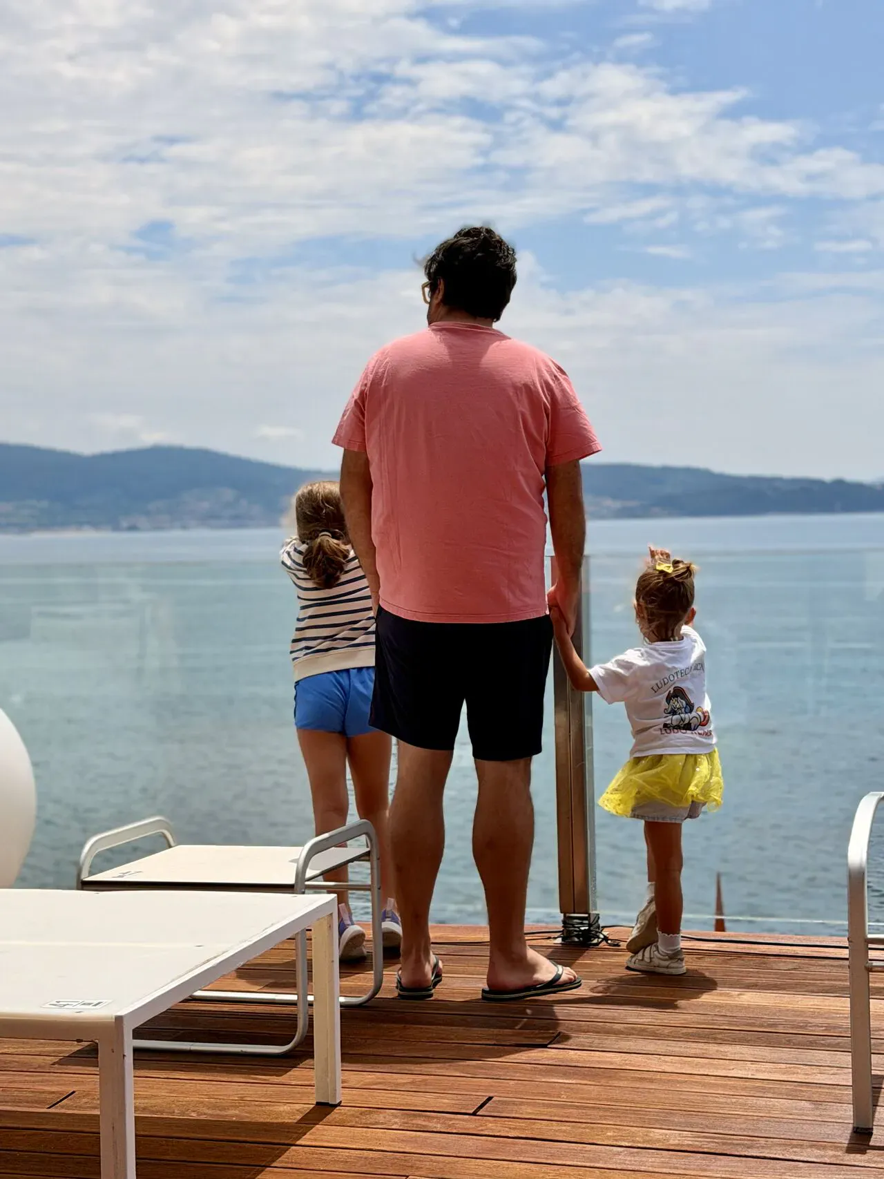 Rafael Tamames de espaldas junto a dos niñas, contemplando el mar durante sus vacaciones