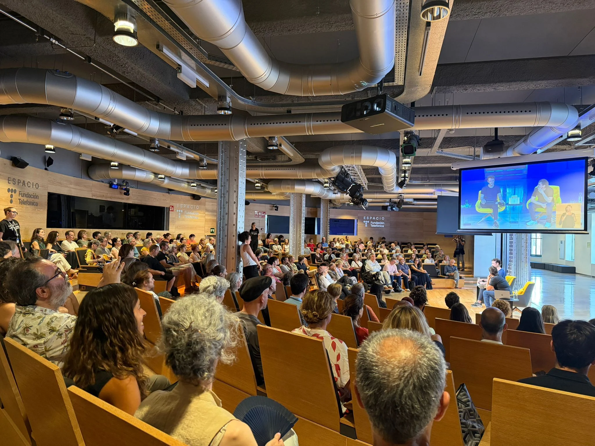 Auditorio lleno en Espacio Fundación Telefónica durante la presentación de Vita, con Xabi Uribe-Etxebarria en el escenario y proyectado en la pantalla