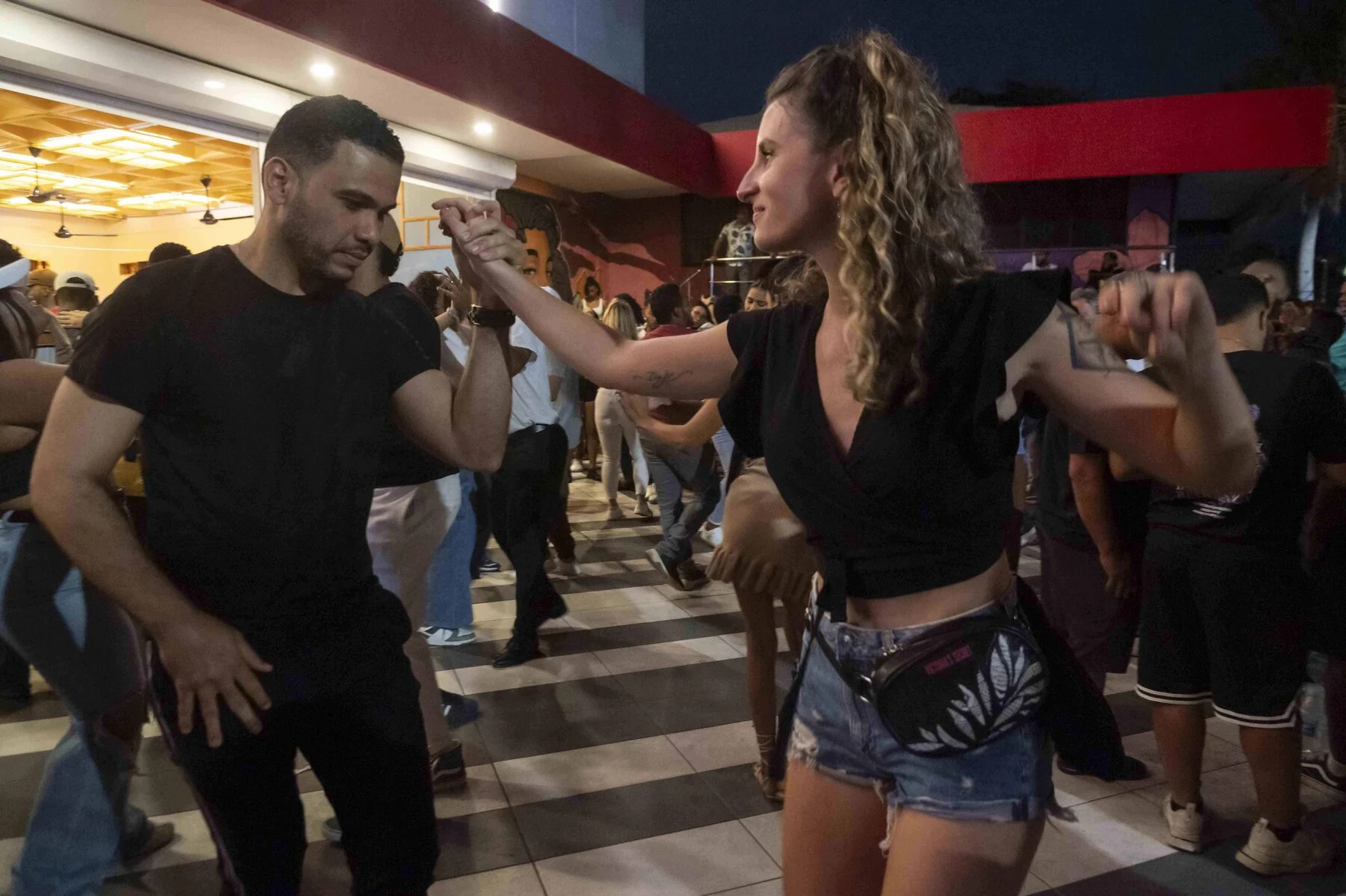 A bachata couple dancing at a busy evening social