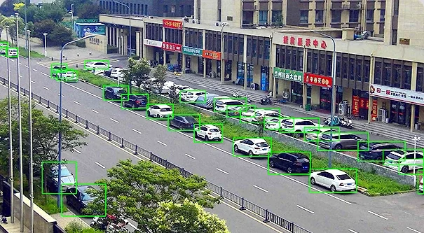Street scene with parked vehicles marked by green detection boxes
