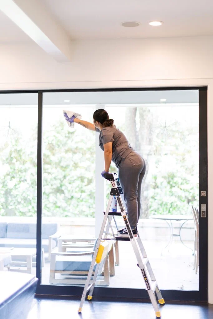 Vella professional cleaning interior window pane with a microfiber cloth after construction in Texas.