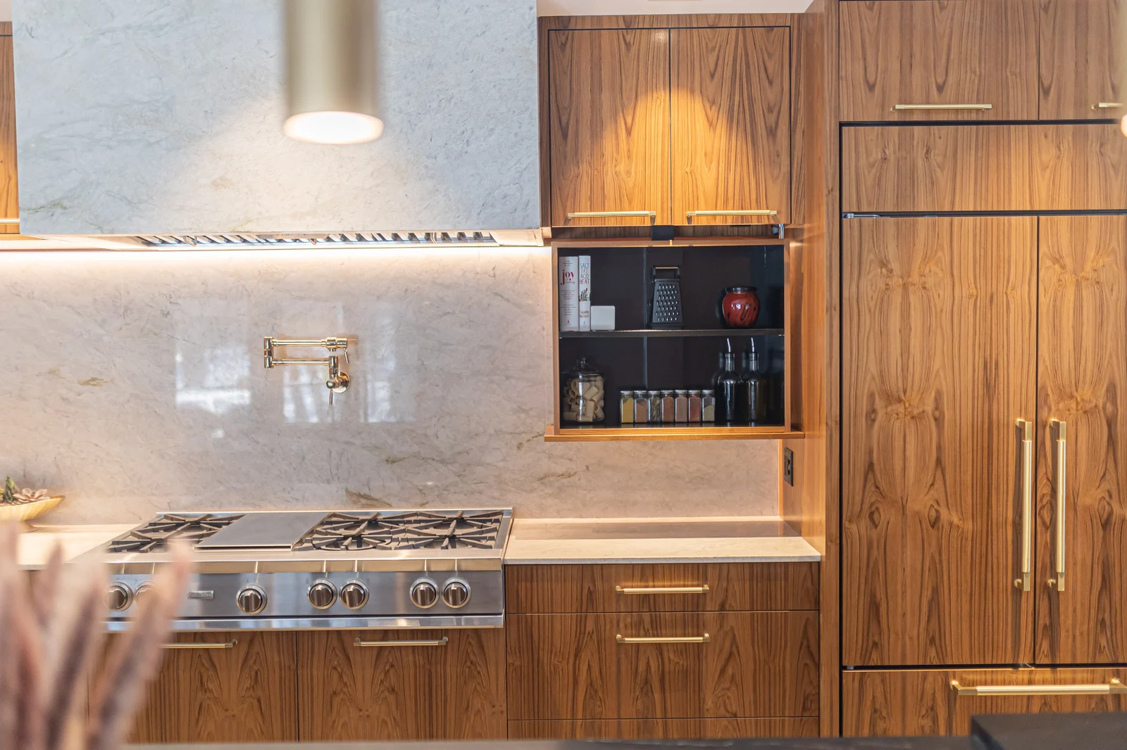 Walnut range cabinetry with brass hardware and a marble backsplash