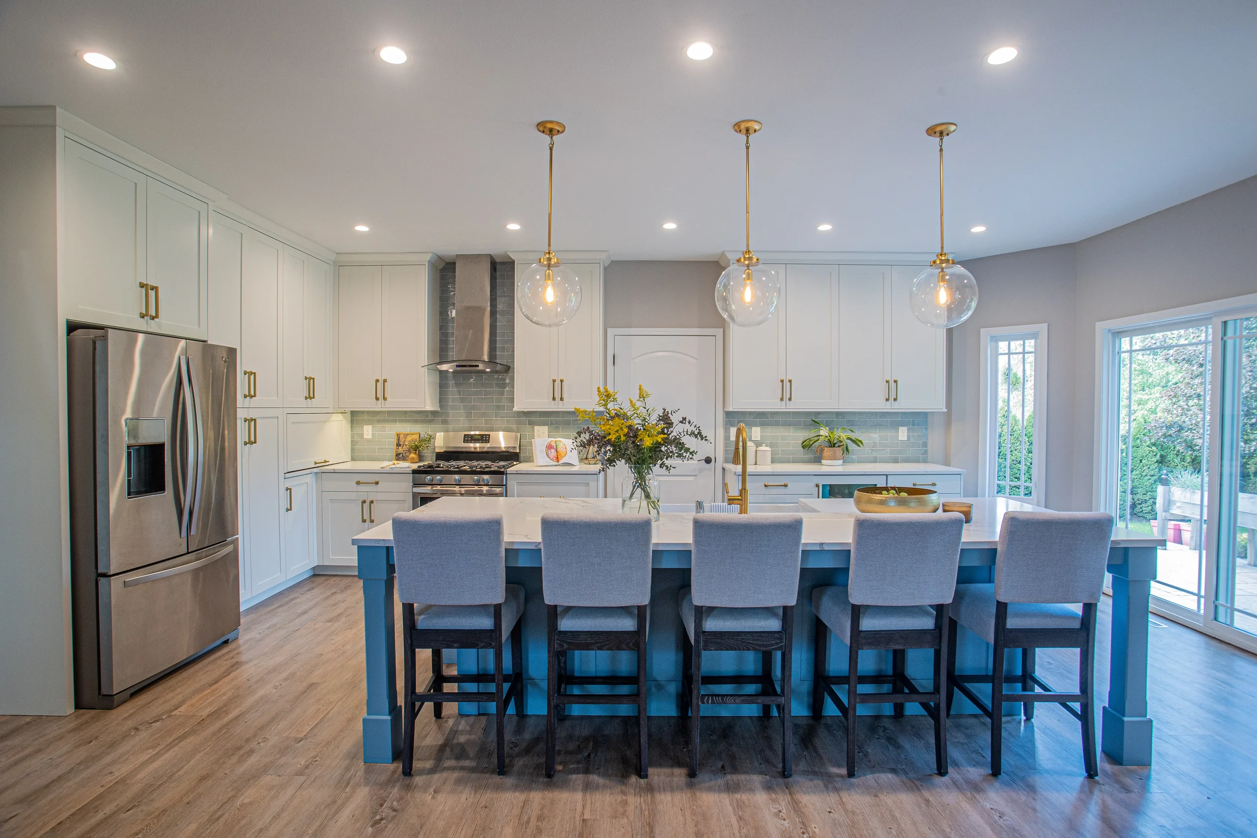 White shaker kitchen with a powder blue island and brass hardware at the Berwick Avenue Residence