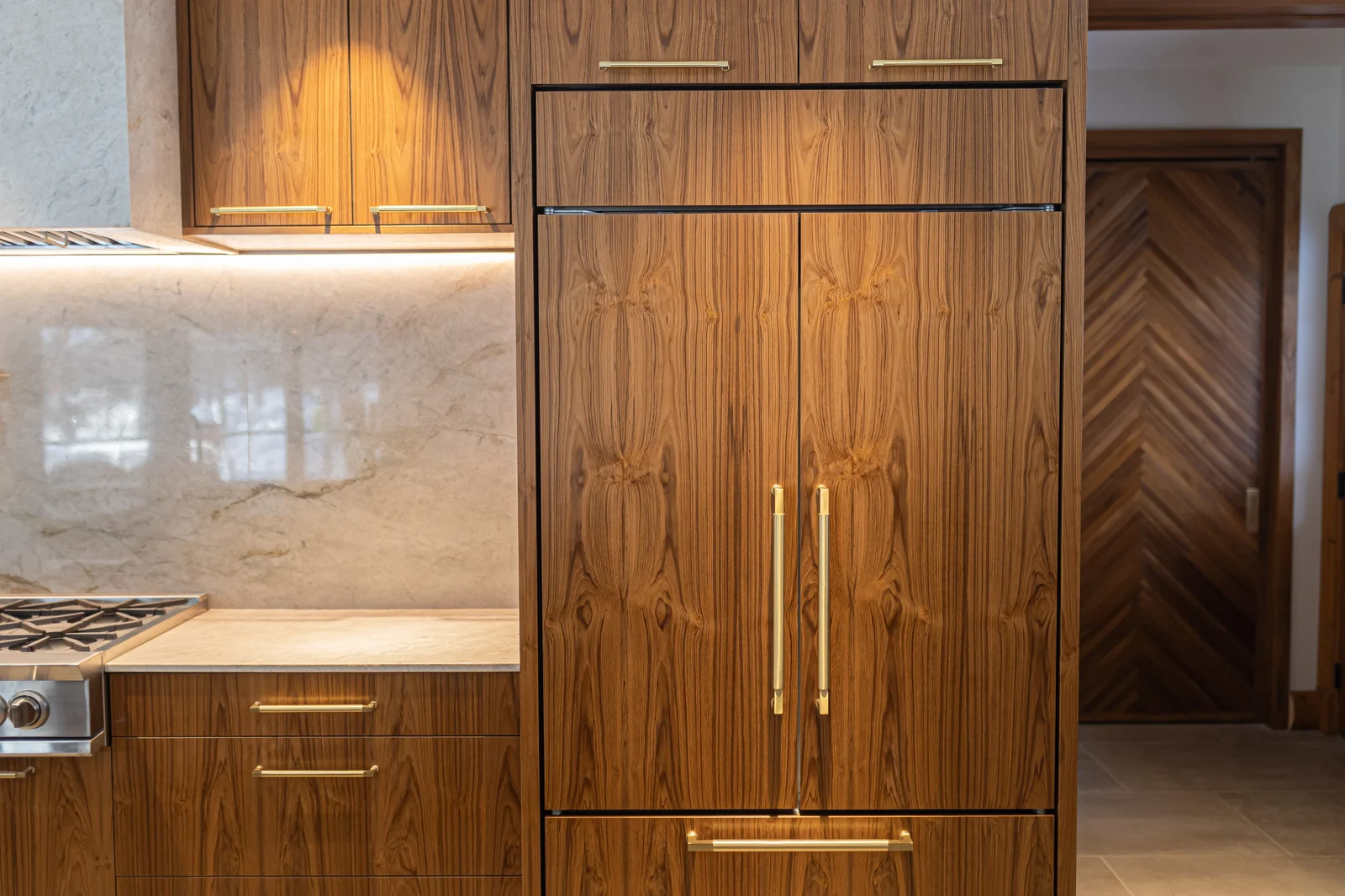 Walnut panels with matched grain concealing the refrigerator