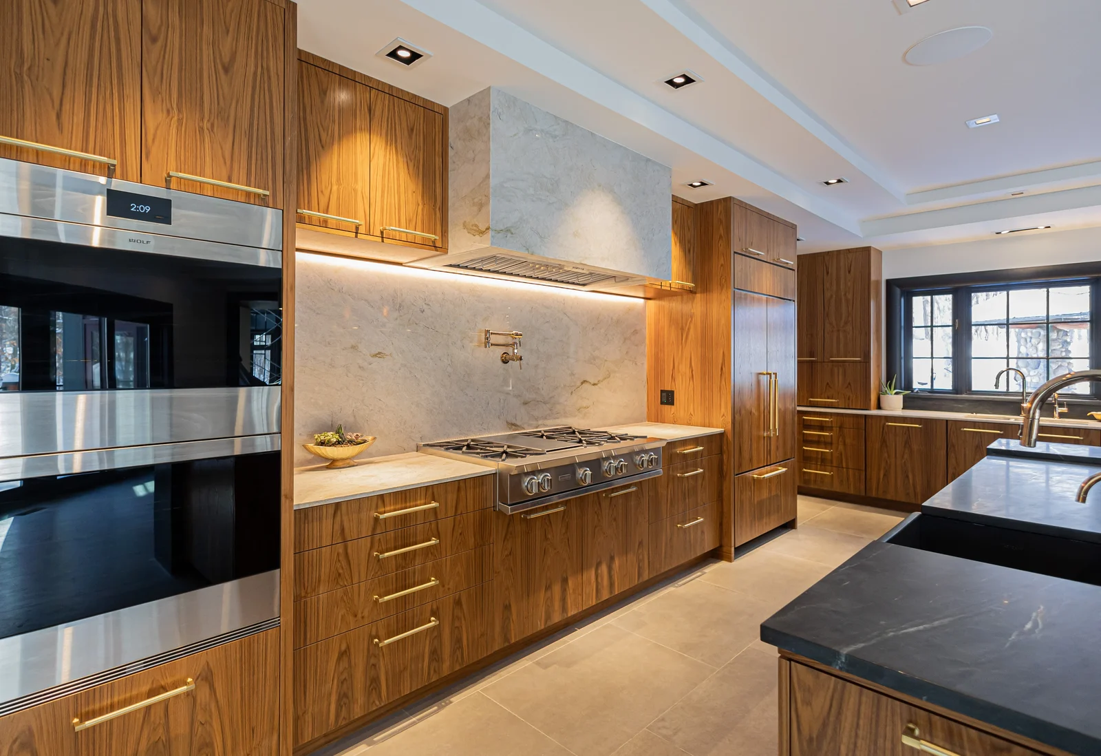 Walnut kitchen with a marble range wall and integrated appliances