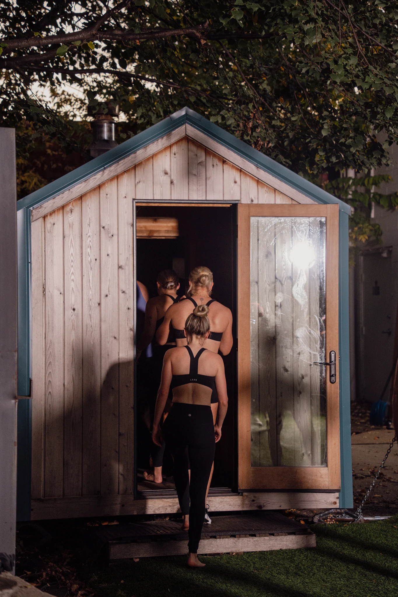 Sauna Strong guests entering the backyard sauna at dusk