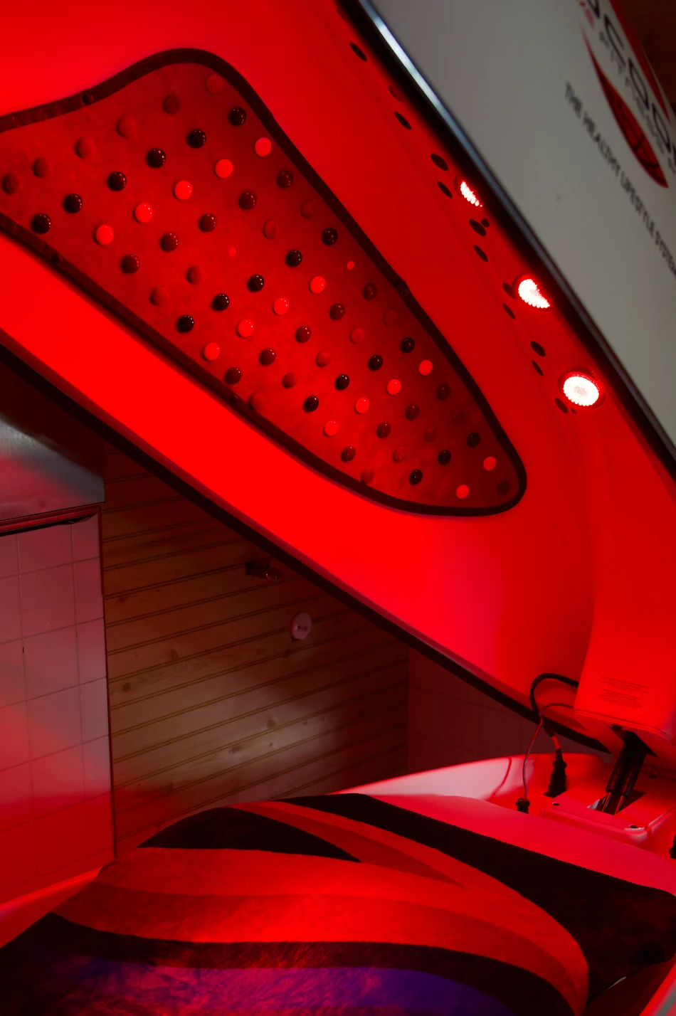 Open Cocoon red light therapy pod showing its glowing light panels and treatment bed at Sauna Strong